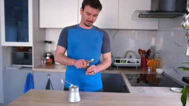 Yakışıklı bir adam teneke bir Türk 'te demlemek için güzel kokulu bir kahve konservesi açıyor. Öğrenci sabahı. Sabah rutinleri. Şık, parlak bir mutfakta duruyor..
