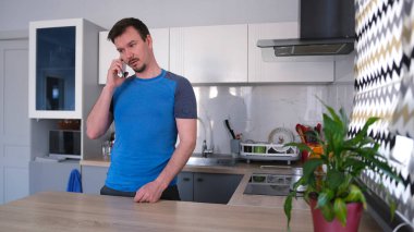 Çekici bir genç adam şık bir mutfakta cep telefonuyla konuşuyor. Kahvaltıda Türk 'te kahve yapıyor. Mutfak temiz ve derli toplu. Masanın üzerinde saksı bitkisi var..