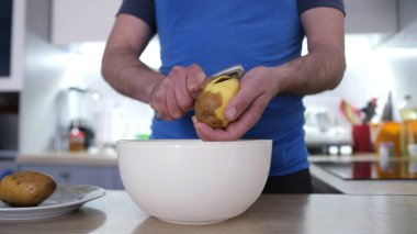 Bir adam çiğ patatesleri yakın plan soyar. Akşam yemeği için kızarmış patates pişirme süreci. Öğrenci yemeği. Nefis bir kahvaltı. Vejetaryen yemeği