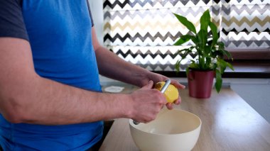 Ev yapımı kızarmış patates pişirme işlemi. Bir adam çiğ patatesleri yakın plan soyar. Kase ahşap bir masanın üzerinde. Lezzetli öğrenci yemeği.