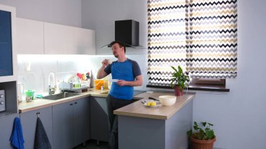 Yakışıklı bir eşcinsel adam mutfakta duruyor ve bir fincan taze ve lezzetli kokulu kahvenin tadını çıkarıyor. Bekar bir adamın sabahı. Bir öğrenci işten önce kahvaltı yapar.