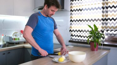 Genç bir şef çiğ patates keser. Kızarmış patates pişirme süreci. Bir adam erkek arkadaşı için lezzetli bir akşam yemeği pişirir. Mutfak temiz ve bakımlı.