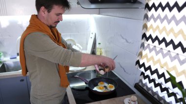 Yağda yumurta. Şirin, yakışıklı bir adam fırının üstünde tavada yumurta pişiriyor. Olay yeri dinlenme yeri. İki kişilik sağlıklı bir kahvaltı hazırlıyorum. Öğrenci