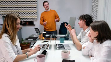 Ofiste sıradan bir gün. Genç profesyonellerden oluşan bir ekip dizüstü bilgisayarlı ve cep telefonlu bir masada oturuyor. Bir adam önlerinde duruyor ve bir sunum yapıyor. Sahne profesyonel ve odaklı.