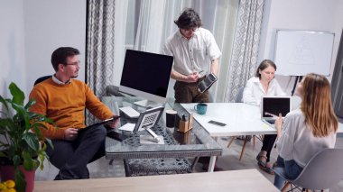 Sabah planlama seansı. Reklam ajansı profesyonellerinden oluşan bir grubun çalışma günü. Tabletleri ve laptopları olan bir grup insan konferans odasındaki bir masada oturuyorlar..