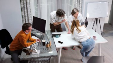 Bir grup insan laptop ekranında bir iş projesini tartışıyor. Olay yeri sakin, insanlar çalışmak ya da sosyalleşmek için bir araya geliyor. Şiddetli fırtına