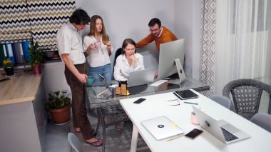 İş kadınının ofisinde bir iş fikrini tartışma fikri. Bir grup insan ev ofisindeki bir masanın etrafında toplandı. Masanın etrafına yayılmış birkaç dizüstü bilgisayar ve cep telefonu var. Bir işbirliği ortamı var.