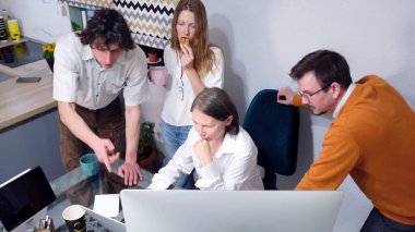 Ofis çalışanları sabah haberlerini tartışıyor. Bir grup insan önlerinde dizüstü bilgisayarla bir masada oturuyor. Bir kadın kurabiye yer ve kahve içer. Beyin fırtınası