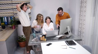 Şaşkın bir ofis çalışanı ekibi patronlarına bir projede yardım ediyor. Bir grup insan patronun bilgisayar monitörünün etrafında toplandı. Beyin fırtınası