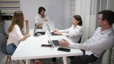 Bir grup genç, başarılı, hırslı insan dizüstü bilgisayarları ve cep telefonlarıyla bir masada oturuyor. Birlikte bir proje üzerinde çalışıyorlar..