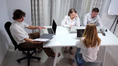 Yöneticilerin toplantısı. Bir finans şirketi. Beyaz gömlekli bir grup insan dizüstü bilgisayarları ve klasörleri olan bir masada oturuyorlar. Sahne odaklı ve profesyonel.