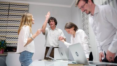 Eğlenceli ofis günleri. Küçük bir işletme şirketinin kurumsal ruhunu yükseltme fikri. Bir grup insan dizüstü bilgisayarlarla bir masanın etrafında toplandı. Grup birlikte çalıştığı için sahne olumlu ve işbirlikçi..