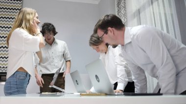 Yöneticiler konferans odasındaki ofis masasına oturdular. Bir grup insan işlerine odaklanmış durumda. Küçük bir şirketin ofis rutini.