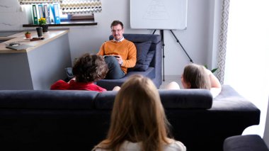 Bir psikologla şirket çalışanlarının gayri resmi toplantısı. İş eğitimi. Bir ekip oluşturma uzmanından tavsiye. Bir adam ve iki kadın oturma odasındaki kanepede oturuyorlar..