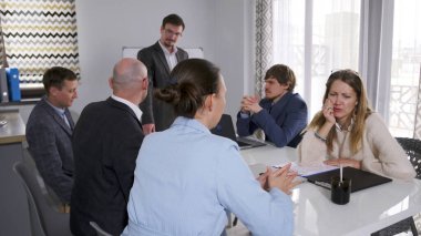 Davet edilen antrenör, grubun kriz ortamındaki etkileşiminin stratejilerini tartışıyor. Birkaç işadamı konferans odasında bir masada oturuyorlar. Uzman danışma