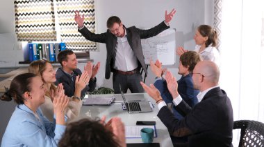 İş ofisindeki mutlu insanlar ihaleyi kazanmayı kutluyorlar. Bir grup insan takım elbiseli başarılı bir adamı alkışlar ve selamlar. Yönetici yüzünde bir gülümsemeyle beyaz tahtanın önünde duruyor.