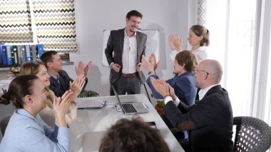Bir grup insan yılın en iyi çalışanını alkışlıyor. Mutlu bir iş adamı meslektaşlarından tebrikleri kabul eder. Takım oluşturma ve takım çalışması.