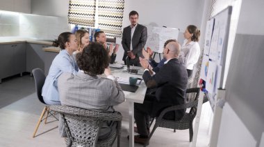 Bir grup ofis çalışanı haftanın en iyi yöneticisini alkışlıyor. Sahne profesyonelce ve işbirliği ruhuyla gerçekleştirilir. Takım oluşturma. Mutlu yıllar.