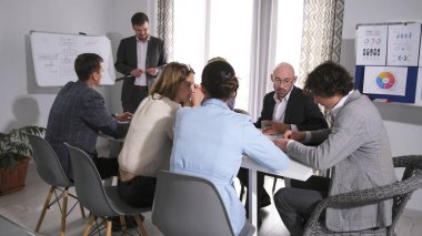 Yenilik, yeniden yapılanma ve karlılık konularının tartışılması. Bir grup başarılı iş adamı konferans odasında bir masada oturuyor. Sahne profesyonel ve odaklı.
