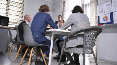 Konferans masasında oturan bir grup iş adamının alt görüntüsü. Grubun bir kriz durumundaki etkileşim stratejisinin tartışılması. Sahne profesyonelce ve işbirliği ruhuyla gerçekleştirilir.