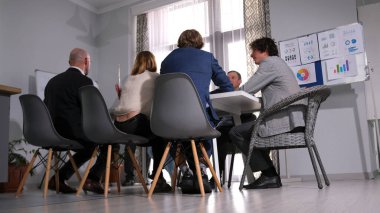 Büyük beyaz bir masada oturan bir grup ofis çalışanının alt görüntüsü. Önemli bir alışverişi tartışıyoruz. Mesleki sorumluluklar.