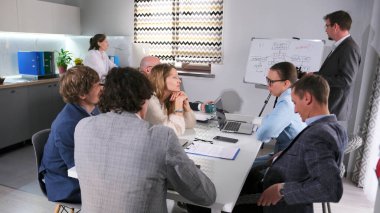 Danışman, bir iş stratejisinin geliştirilmesi üzerine bir sunum yapar. İş adamları müzakere masasında iletişim kurar. Küçük bir ev ofisi..