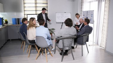 Koç, grubun bir kriz ortamındaki etkileşiminin stratejilerini tartışıyor. Bir grup genç iş adamı bir okutman etrafında oturuyor. Bir psikolog sunum yapar.