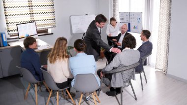 Bir grup insan bir akıl hocası ve beyaz tahtanın etrafında sandalyelerde oturuyor. Merkezdeki adam bir sunum yapıyor. Takım oluşturma. İş konsepti.