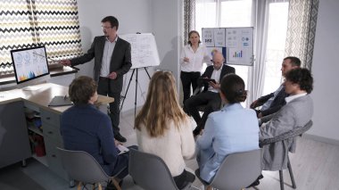 Bir grup insan konferans odasında sandalyelerde oturuyor ve bir akıl hocasının sunumunu dinliyor. Koçun koçu. Takım oluşturma. İş konsepti