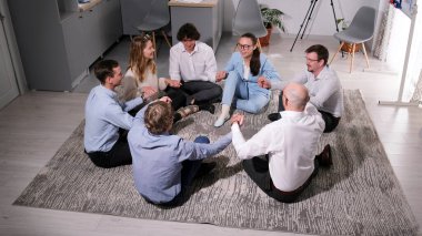 Bir grup başarılı girişimci aile ofisindeki bir paspasın üzerinde el ele tutuşuyorlar. Karşılıklı destek ve saygı. Öğretim üyesinden danışma