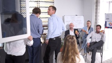 Bir grup insan aile ofisinin mutfağında akşam yemeği yemek için toplandı. Takım oluşturma molasında iş yemeği. Sahne rahat ve sosyal, grup birbirinin arkadaşlığından hoşlanıyor ve fikirleri tartışıyor..