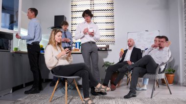 İş arkadaşları ofis mutfağında öğle yemeği yiyorlar. Aile ofisinde iş yemeği. Yorgun şirket çalışanları sandviç yiyor, salata yiyor ve kahve içiyor. Atmosfer rahat.