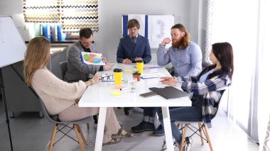 Müdürün ofisinde sabah toplantısı. Bir grup genç uzman konferans odasında bir masada oturmuş şirketin geliştirme stratejisini tartışıyorlar..