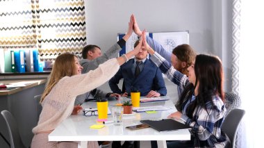 Beyaz bir masadaki pozitif bir grup insan birbirine beşlik çakıyor. Takım oluşturma ve takım çalışması. Kendi alanlarındaki profesyoneller. Aile işyeri