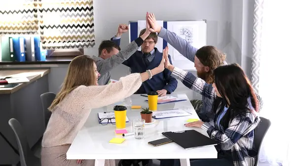 Bir grup genç iş adamı toplantı odasında bir masada oturup birbirlerine beşlik çakıyorlar. Sahne olumlu ve dostane. Başarılı bir alışveriş. Takım çalışması.