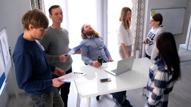 Zor bir gündü. Elinde bir bardak kahve olan yorgun bir bölüm başkanı masa başında bir ofis sandalyesinde oturuyor ve astları etrafında dolanıyor..