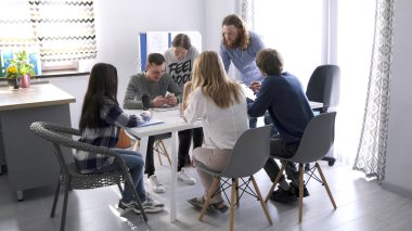Küçük bir aile ofisinde büyük bir proje üzerinde çalışıyorum. Genç erkekler ve kadınlar birlikte çalışmak için aynı masada toplandılar. Takım oluşturma ve beyin fırtınası.