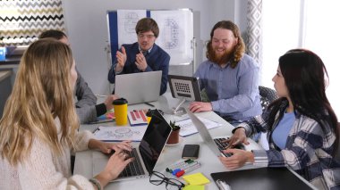 Genç, pozitif ve başarılı bir profesyonel takım. Bir grup insan aile ofisinin konferans odasında bir masada oturuyor ve dizüstü bilgisayarlarla ilgili bir proje üzerinde çalışıyorlar.