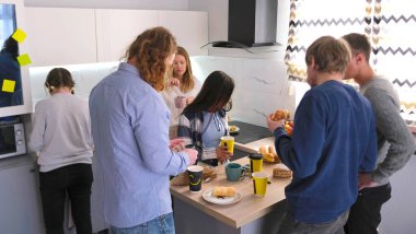 İş yemeği. Kahve molası. Yaratıcı bir grup genç müteahhit öğle yemeği yemek ve sohbet etmek için ofis mutfağına geldi. İşte bir mola. Sahne rahat ve dost canlısı.