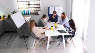 Bir grup öğrenci bir girişimi tartışıyorlar. Genç girişimciler toplantı odasında oturuyorlar ve ortak bir proje üzerinde çalışıyorlar. Sahne işbirliği ve odaklanma için tasarlandı.