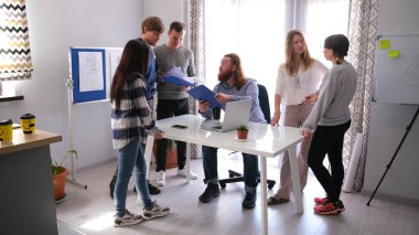 Patron sabah toplantısı için şirket çalışanlarını çağırdı. Genç çalışanlar birbirleriyle iletişim kurarlar ve patronun emirlerini dinlerler. Takım çalışması.