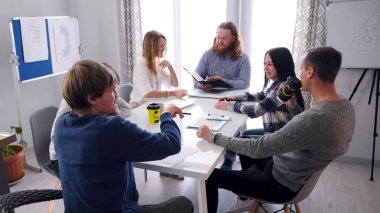 Mutlu reklam ekibi toplantıda gülümsüyor. Bir grup güzel genç insan aile ofisindeki bir masada oturuyorlar. Sahne rahat ve doğal.