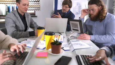 Üç işadamı dizüstü bilgisayarlarla bir masada oturmuş önemli bir anlaşmayı tartışıyorlar. Genç girişimciler bir girişim üzerinde çalışıyorlar. Beyin fırtınası.