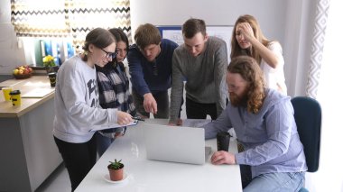 Beyin fırtınası seansı. Genç yaratıcı bir grup insan bir dizüstü bilgisayarla masanın etrafında toplandı ve dikkatlice ona baktı. Takım çalışması. Normal bir iş günü.
