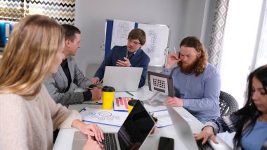 Şirket personeli dizüstü bilgisayarları üzerinde sıkı çalıştığı için sahne odaklı ve ciddi. Bir grup insan aile ofisindeki bir masada oturuyor..