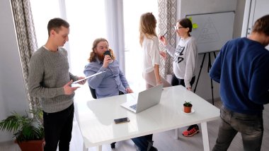 Genel müdür meslektaşları birbirleriyle iletişim kurarken kahve içer. Sahne işbirliği ve odaklanma için tasarlandı. Bir grup insan beyaz bir tahtayla masanın etrafında toplandı.