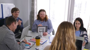 Modern bir iş ofisinde beyin fırtınası ve takım çalışması. Bir grup yakışıklı genç adam dizüstü bilgisayarlar ve tabletlerle bir masada oturuyorlar. Menajerlerin çalışma günleri