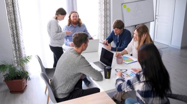 Takım çalışması. Bir reklam ajansı. Bir grup insan aile ofisinde bir masada oturuyor ve birlikte bir proje üzerinde çalışıyorlar. İşbirliği atmosferi