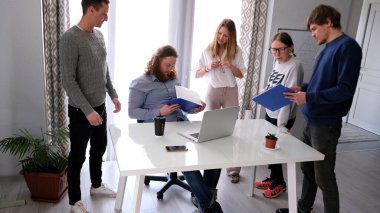 Şirketin lideri astlarının tepkilerini gözden geçirir. Sabah brifingi. Bir grup insan toplantı için müdürün masasının etrafında toplandı..