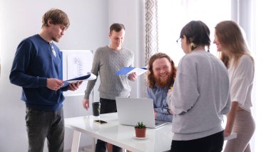 Mutlu patron genç uzmanlardan oluşan profesyonel takımı için mutlu. Takım çalışması. Sabah brifingi. Bir grup insan müdürün masasının etrafında duruyor.